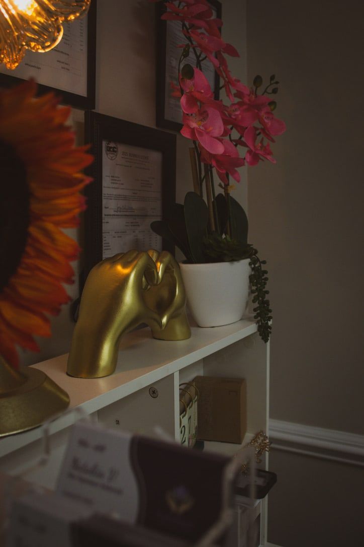 A gold cupped-hands heart sculpture beside Nataliia's framed certifications