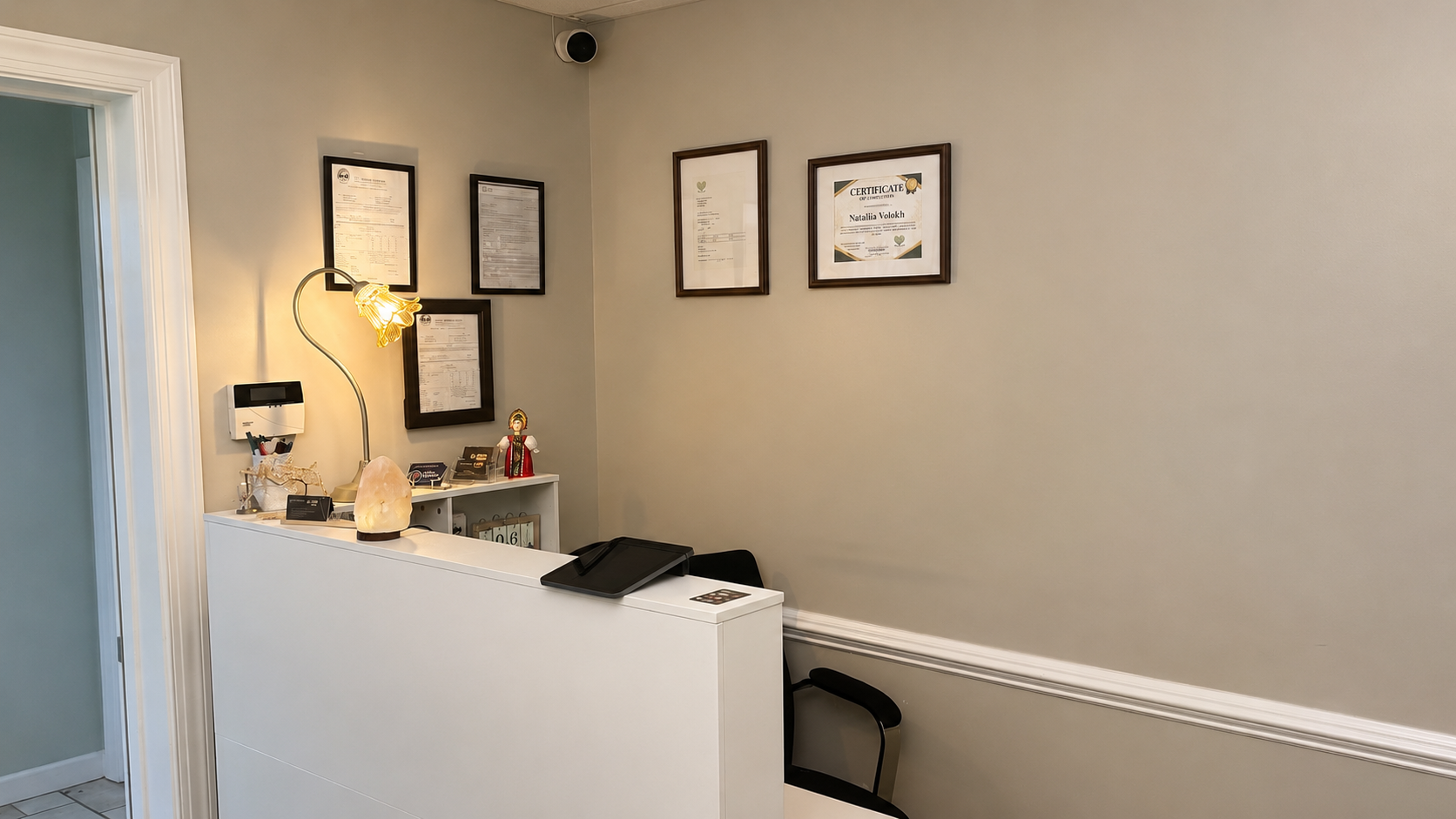 The reception desk with a Himalayan-salt lamp and Nataliia Volokh's framed certifications on the wall